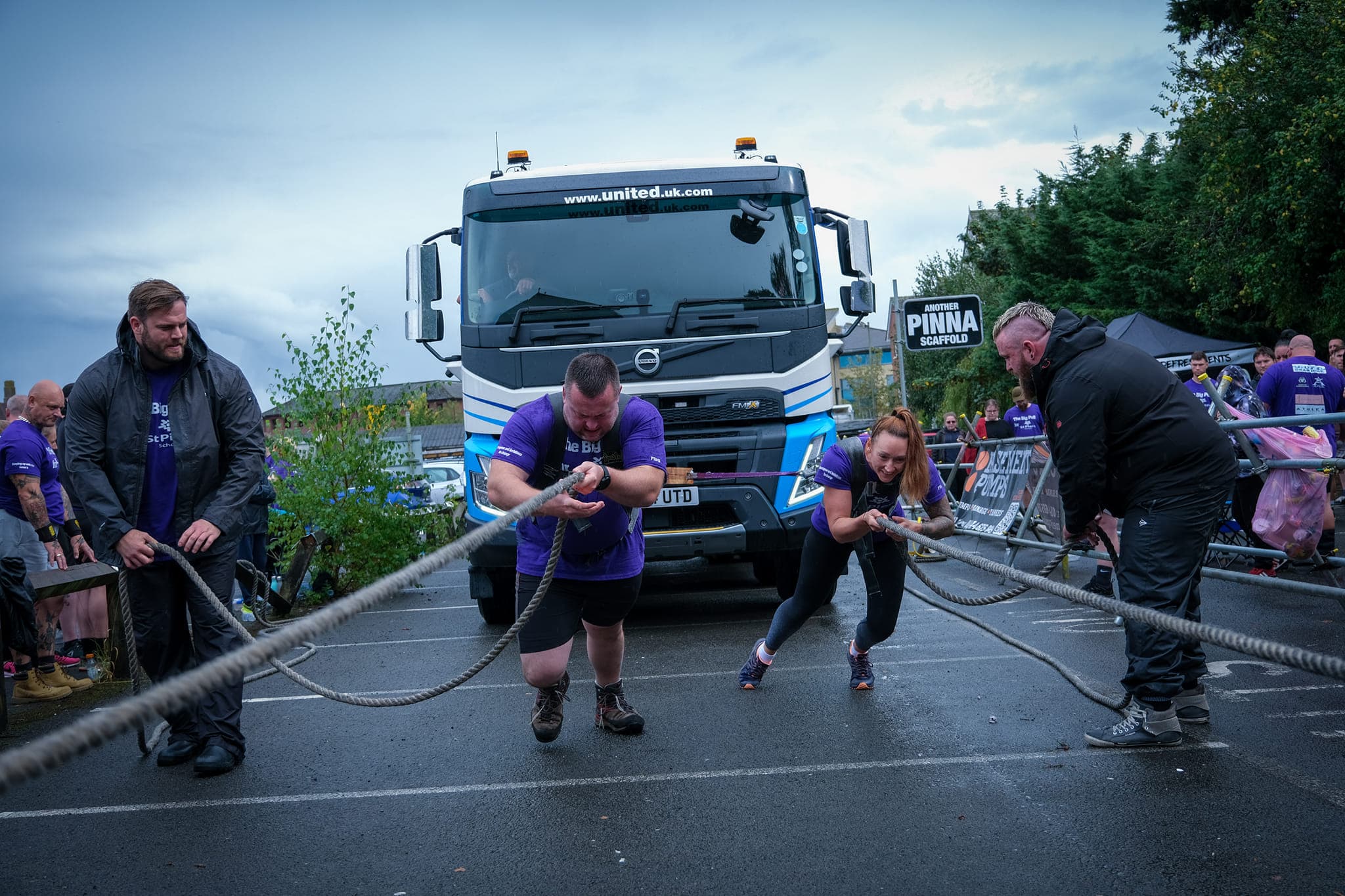 Big Pull team mid-truck-pull on a United Volvo, purple shirts, dramatic sky