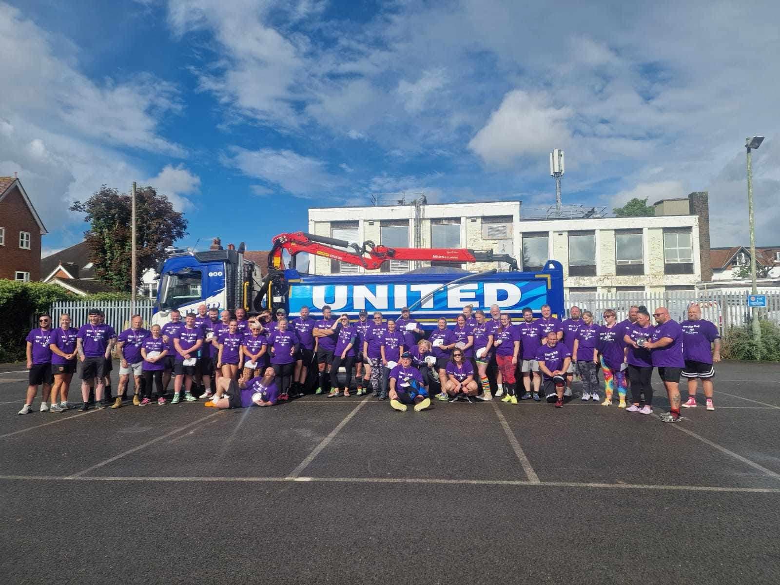 Big group photo — purple Big Pull for Sands shirts in front of a United truck